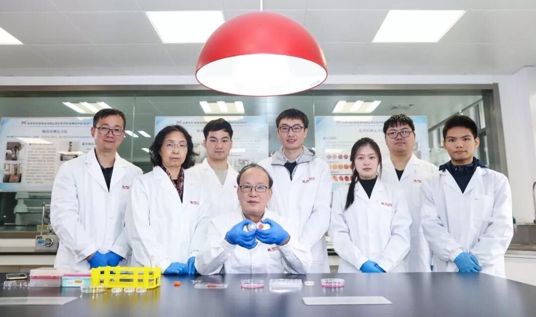 Asian scientists standing behind a lab table looking into the camera