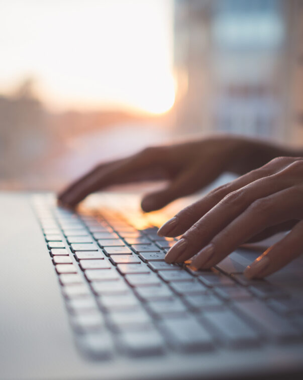 Woman working at home office hand on keyboard close up.