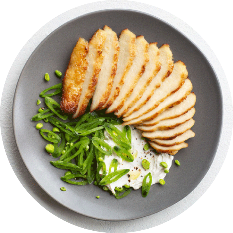 Overhead shot of cultivated chicken with greens in a bowl