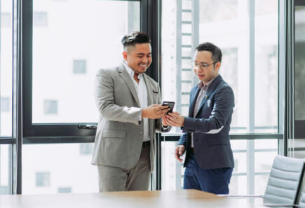 Two professionally dressed Asian men looking at something on a mobile device