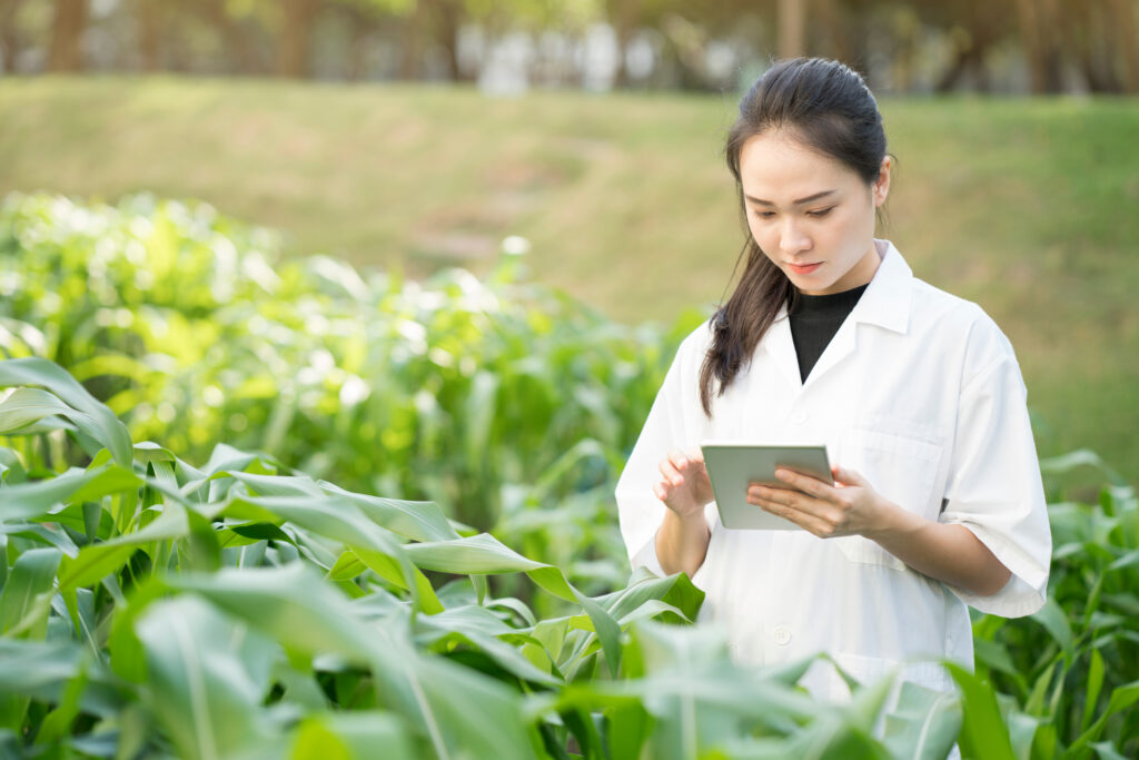 Asian woman taking notes on a small computing device in a field