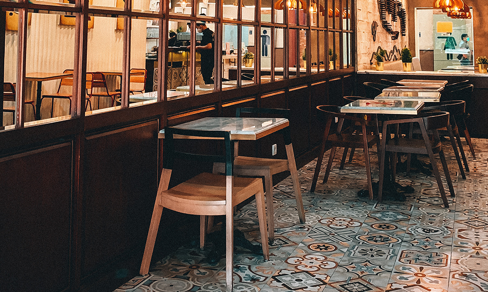 Interior of an empty Asian restaurant with a couple of employees in background.